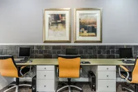 Contemporary home office with stylish wooden chairs, sleek computers, and abstract art for a modern workspace.