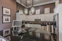 Elegant modern kitchen with sleek granite countertops, stainless steel appliances, and stylish lantern pendant lighting.