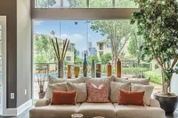 Luxurious living room with plush sofa, elegant decor, and expansive windows offering a stunning view of the garden and city skyline.