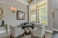 Elegant and cozy apartment lounge featuring plush seating, stylish decor, and large windows with serene garden views.