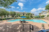 Inviting residential community with serene swimming pool, lush greenery, and spacious lounging areas under a bright blue sky.
