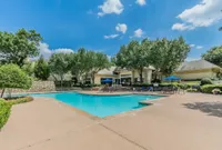 Inviting outdoor pool area surrounded by lush greenery and elegant patio seating, perfect for relaxation and leisure.