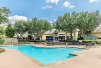 Inviting luxury apartment complex showcasing a sparkling swimming pool, elegant outdoor seating, and lush greenery, perfect for relaxation and leisure.