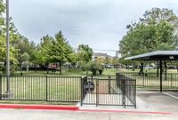 Designed with Pets (and Their People) in Mind Inviting community park entrance with lush green landscaping and contemporary fencing, perfect for outdoor enjoyment.