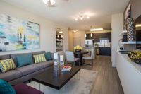 Contemporary Style, Everyday Ease Elegant living area with contemporary decor, featuring a plush sofa, vibrant artwork, and an open concept kitchen with sleek cabinetry.