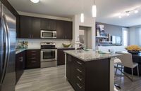 Cook, Dine, Entertain—Your Way Modern kitchen featuring sleek dark wood cabinets, granite countertops, and stainless steel appliances, opening into a stylish dining area for luxurious living.