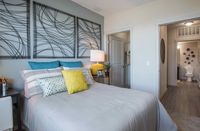 Your Sanctuary Awaits Inviting bedroom with elegant decor, modern art, and bright accents, featuring a cozy bed with colorful cushions and a stylish nightstand.