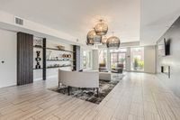 Sophisticated Spaces, Effortless Comfort Elegant living room featuring modern decor, a stylish lounge area with plush seating, decorative shelving, and large windows filling the space with natural light.
