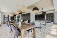 Community Starts Here Chic modern apartment lounge with elegant wooden tables, plush seating, stylish pendant lighting, and a cozy entertainment area.