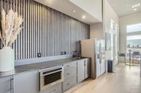 Host. Chill. Connect. Modern kitchen with sleek cabinetry, stainless steel appliances, and a bright dining nook with large windows.