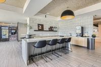 Daily perks served here Modern communal kitchen space with elegant bar seating, sleek countertops, and a gourmet coffee station.