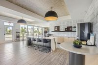 Fuel up on-site Bright and modern communal kitchen space with sleek countertops, bar seating, and natural light through large windows.
