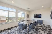 Work From Home, Without the Distractions Bright and modern meeting room with large windows, elegant furnishings, and a stunning city view, perfect for professionals.