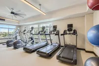 Sweat, Sculpt, Repeat Modern fitness center with state-of-the-art treadmills and elliptical machines, featuring large windows for natural light and an inviting, spacious atmosphere.