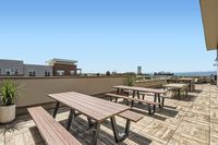 Where Fresh Air Meets Fine Living Inviting rooftop terrace with modern picnic tables and panoramic city views, perfect for outdoor gatherings and relaxation.