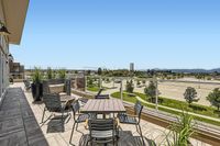 Breathe In. Chill Out. Expansive terrace with stylish seating, offering panoramic views of a vibrant cityscape under a clear blue sky.