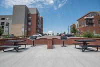 Outdoor Living & Grilling Stations Modern apartment complex featuring stylish brick architecture, ample parking, and outdoor amenities including picnic tables and grills, set under a bright blue sky.
