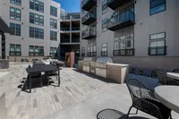 Modern apartment courtyard featuring stylish outdoor seating, sleek dining area, and state-of-the-art grills for a luxurious lifestyle.