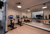 Modern fitness room with two high-tech stationary bikes, wall-length mirror, and sleek wooden flooring for an inspiring workout atmosphere.
