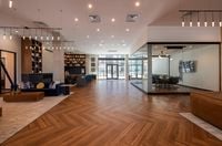 Luxurious open-concept living space featuring elegant herringbone wood flooring, modern lighting, a contemporary seating area, and a chic glass-walled conference room.