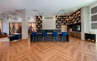 Modern apartment lounge with sleek wooden flooring, stylish bar seating, and geometric shelving, offering a chic and inviting atmosphere.