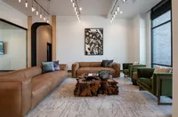 Contemporary living room with stylish brown leather sofas, unique wooden coffee table, and modern art accentuated by elegant lighting.