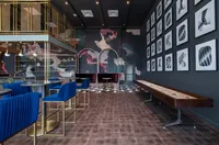 Modern and artistic lounge with sophisticated decor, featuring elegant blue velvet seating, chic pendant lights, and a sleek shuffleboard table.