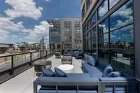 Luxurious modern rooftop terrace featuring chic blue seating, expansive views, and a vibrant urban skyline.