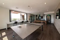 Bright recreational room with large windows, featuring a ping pong table, pool table, and outdoor view seating.