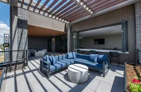 Modern outdoor terrace with stylish blue seating, sleek design accents, and open access to a chic indoor lounge.