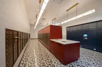 Modern mailroom with stylish geometric tile flooring, sleek red and blue lockers, and elegant overhead lighting.