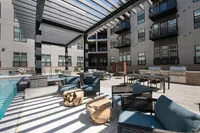 Modern apartment courtyard with stylish pergola, comfortable seating, and inviting poolside lounge area.