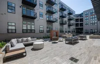 Modern apartment building with stylish balconies, featuring a chic outdoor lounge area with comfortable seating and a grill, perfect for entertaining.