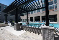 Luxurious apartment pool area featuring a modern pergola, stylish poolside seating, and sleek architectural elements.