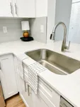 Cook in Style Modern kitchen corner with sleek stainless steel faucet, elegant white cabinetry, and chic subway tile backsplash, accented by a stylish table lamp.