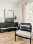 Living Spaces That Inspire Chic living space with elegant decor, featuring a modern black chair, stylish console, and artistic wall painting, complemented by natural light.