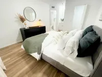 Serene Spaces for Rest and Recharge Chic bedroom with elegant decor featuring a plush bed with soft pillows, stylish dresser with a round mirror, and cozy ambiance.