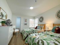 Cozy and versatile Bright and cheerful bedroom with twin beds, tropical leaf bedding, and playful stuffed animals creating a cozy atmosphere.