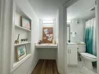 Sleek, Sophisticated, and Functional Charming hallway with decorative shelving and a cozy workspace leading to a modern bathroom with elegant finishes.