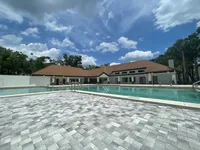Dive Into Relaxation Inviting outdoor pool area with modern paver deck and spacious clubhouse under a bright blue sky.