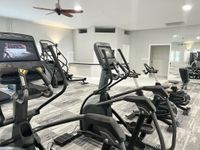 Sweat, Sculpt, Repeat Modern apartment gym equipped with state-of-the-art exercise machines, sleek design, and ample natural light.