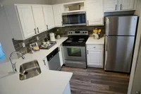 Cabinet Space That Works Overtime Modern kitchen with sleek stainless steel appliances, elegant white cabinetry, and stylish dark tile backsplash.