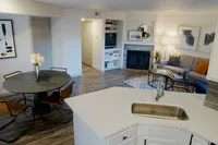 Seamlessly Connected Living & Dining Inviting open-concept living space featuring a modern kitchen with sleek countertops, a cozy seating area by the fireplace, and stylish dining setup.