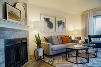 Bright, Open Floor Plans Cozy and stylish living room featuring a comfortable gray sofa with vibrant cushions, elegant fireplace, and modern decor accents.