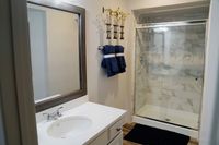 Start and End Your Day in Style Elegant bathroom with a sleek marble-tiled shower, large mirror, and stylish modern sink.