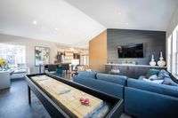 Where Neighbors Become Teammates Luxurious open-plan living area featuring modern decor, a comfortable seating space, a wall-mounted TV, and a stylish game table, ideal for entertaining.