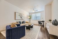 Inviting living room with elegant decor, featuring a plush blue and beige sofa set, modern artwork, and natural light streaming through a window.