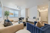 Inviting living room with elegant decor, featuring a plush sofa, stylish armchair, and a cozy workspace, perfect for relaxation and productivity.