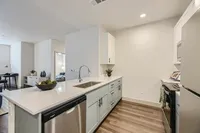 Modern kitchen with sleek stainless steel appliances, elegant countertops, and ample storage, seamlessly connected to inviting living space.