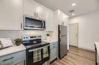 Modern kitchen with sleek stainless steel appliances, elegant white cabinetry, and stylish tile backsplash.